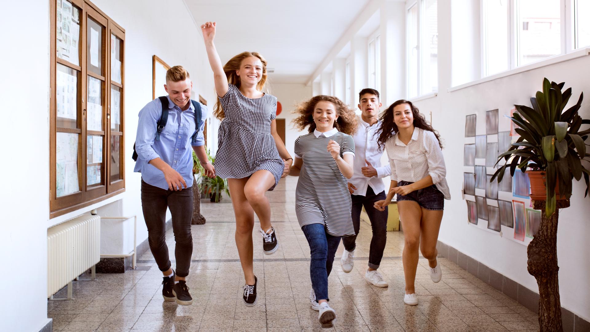 Teenage students in high school hall jumping high.